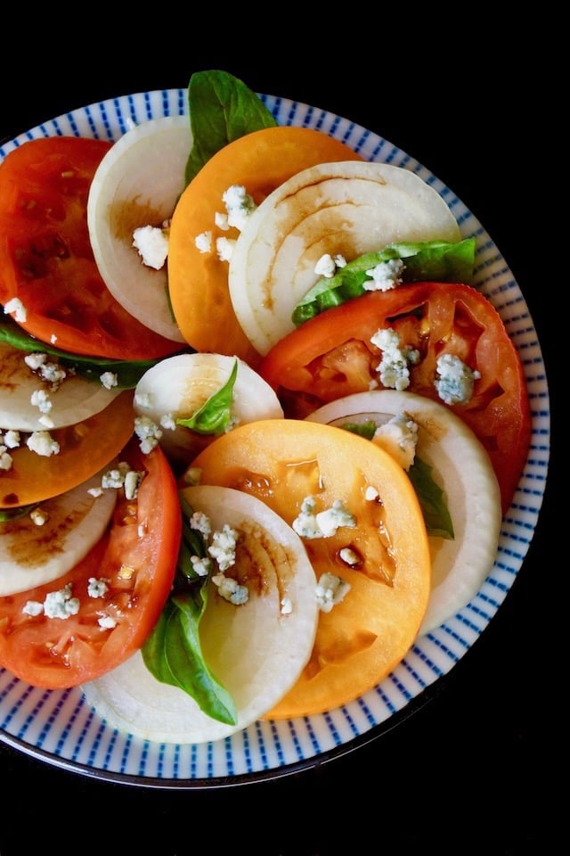 red and yellow Tomato Onion Blue Cheese Salad on pretty blue plate