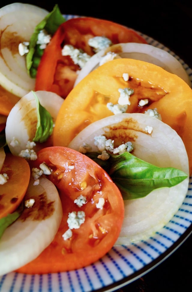 red and yellow Tomato Onion Blue Cheese Salad on pretty blue plate