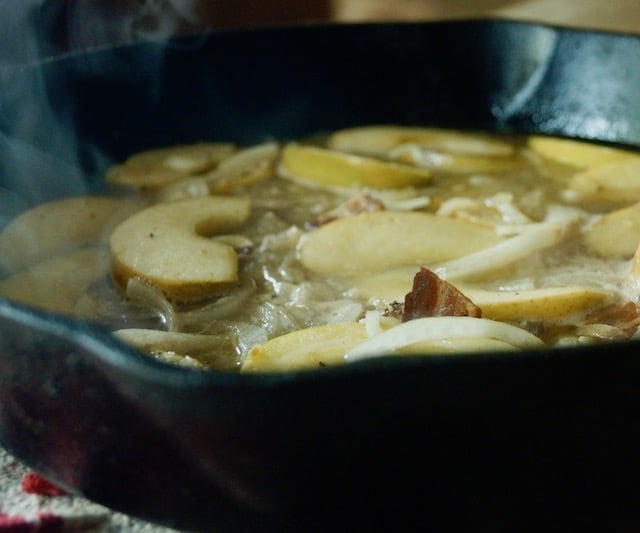 Cast iron skillet with apples slices, with steam.