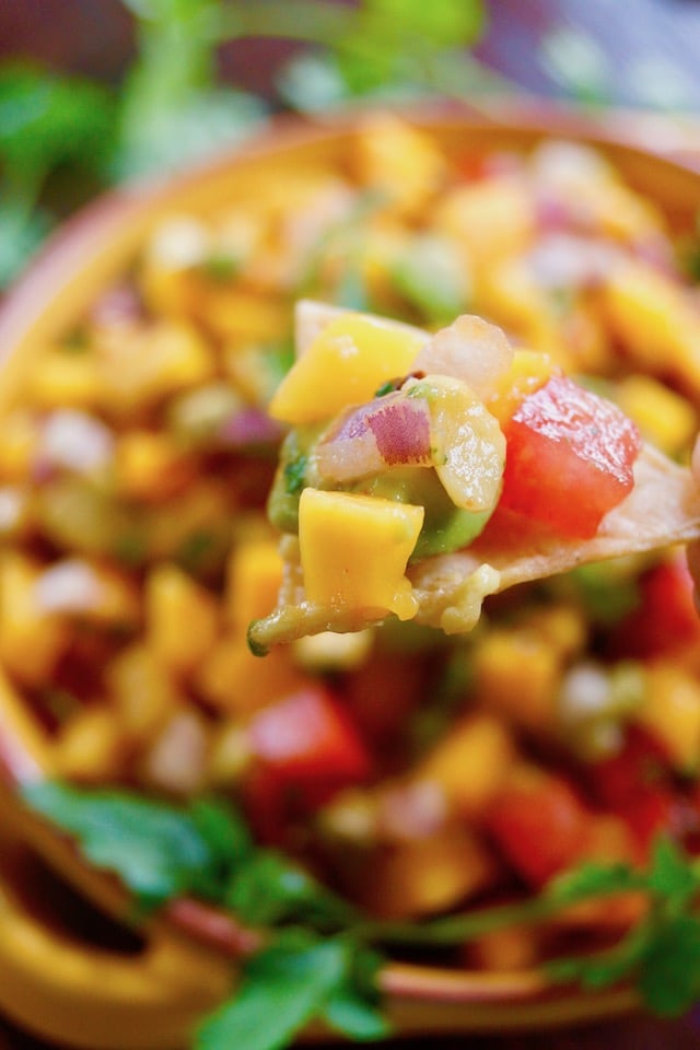 Mango Avocado Chipotle Salsa on a chip and in a bowl below it.