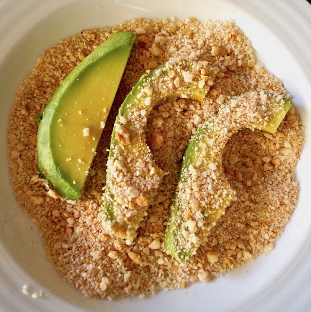 Avocado slices being coated with gluten-free breadcrumb mixture