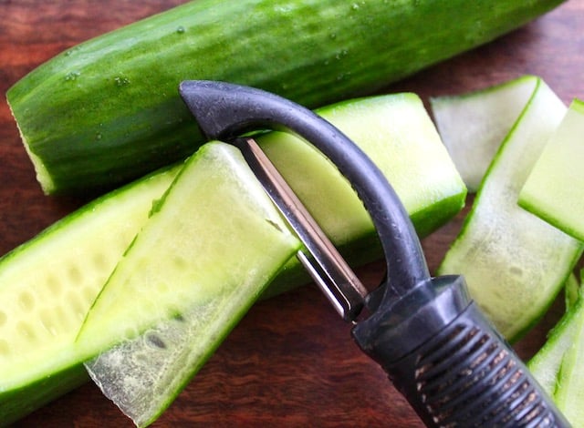 Cucumber being slices with a vegetable peeler