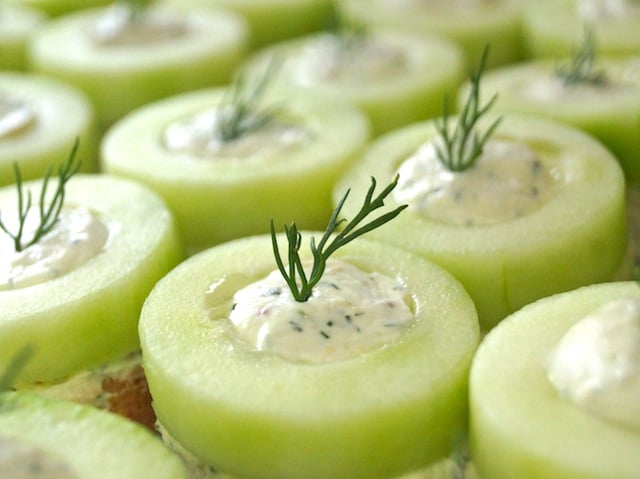 Cucumber Dill Canapes lined up in rows with dill sprigs in each one.