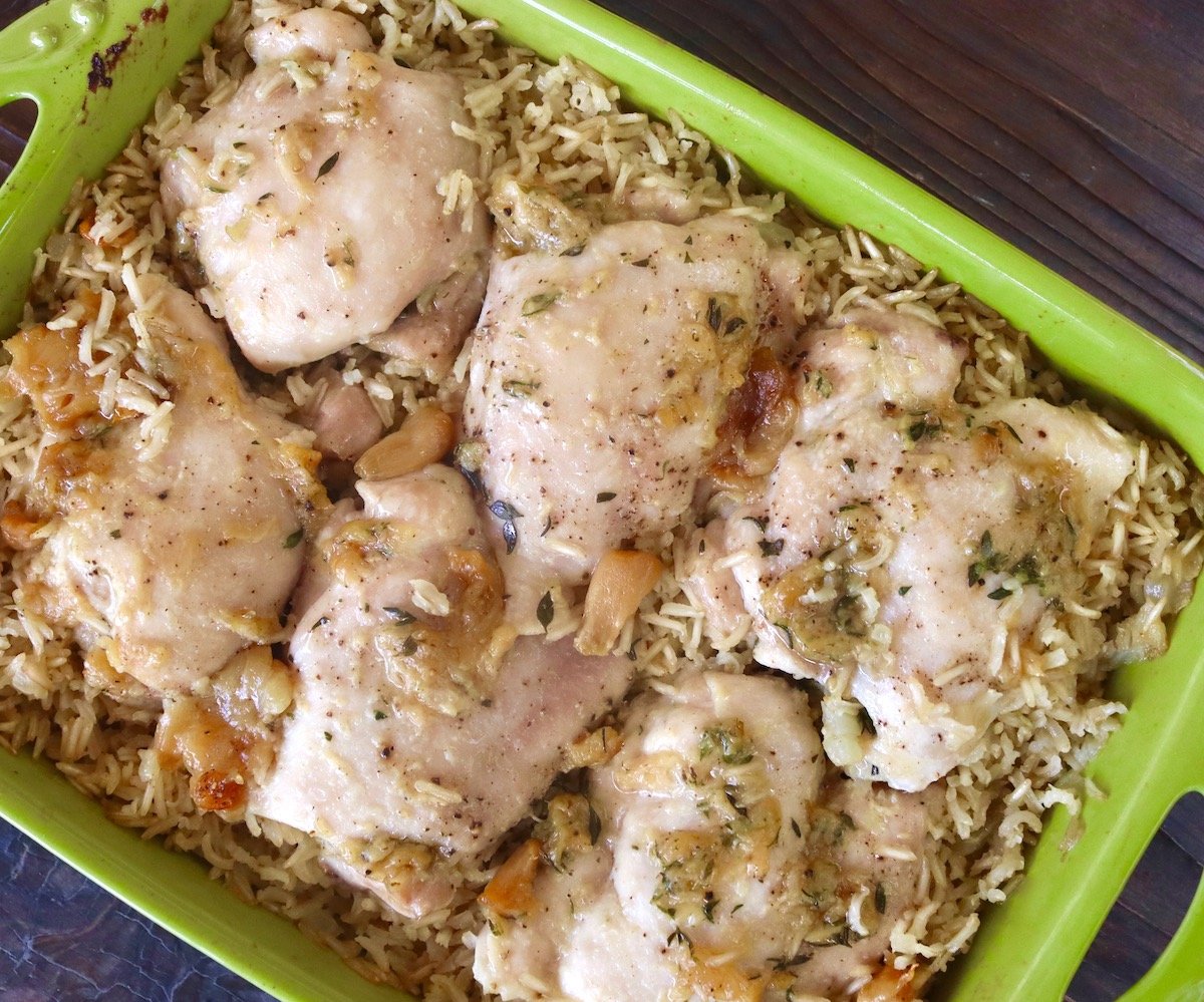 Baked garlic chicken and rice in green casserole dish.