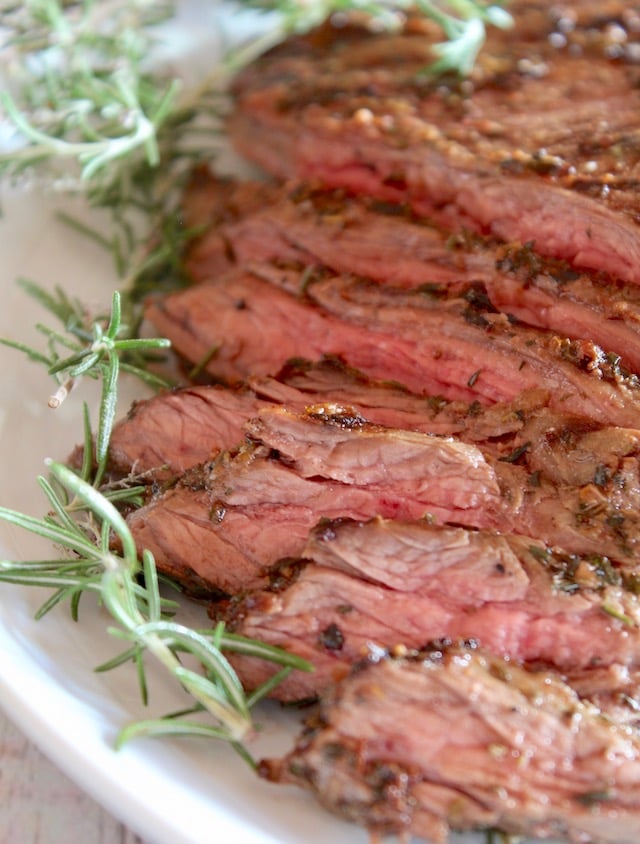 sliced mediterranean marinated steak with fresh rosemary