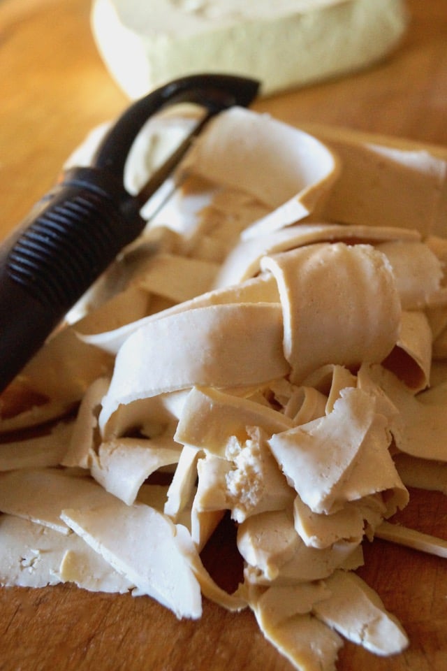 Pile of tofu that's bee cut into noodles on a wooden board.