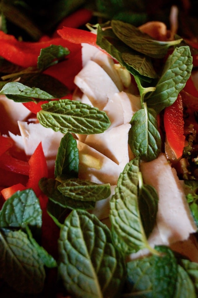 Thinly sliced tofu and red peppers with fresh mint leaves, in a pan.