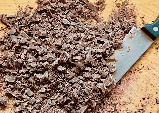 Finely chopped bittersweet chocoalte on cutting board with knife