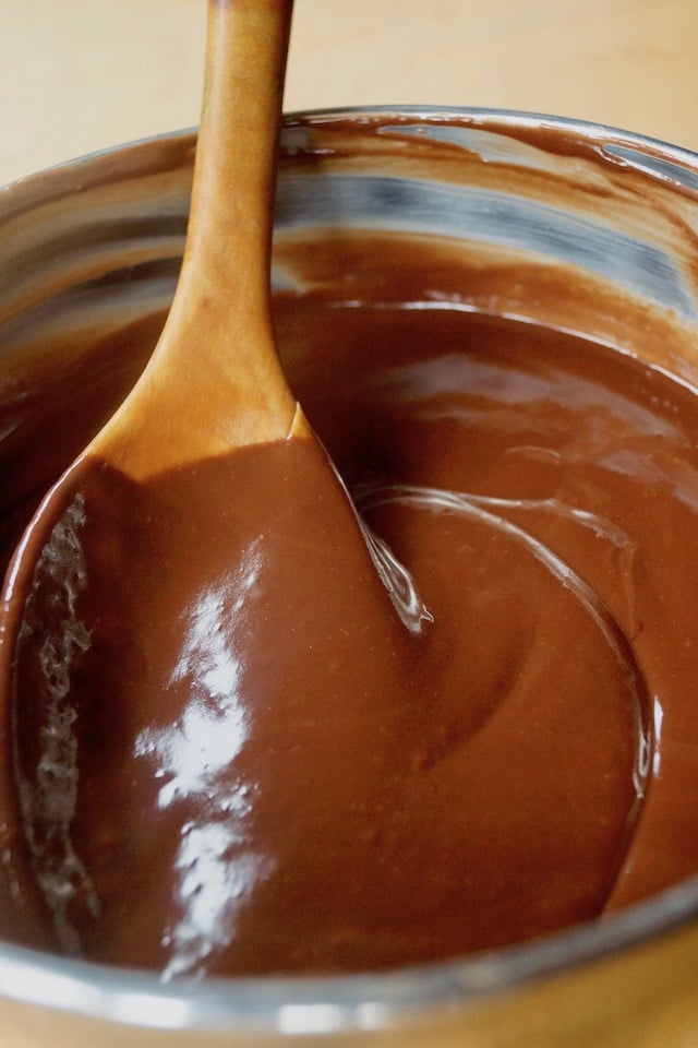 Ganache in stainless steel bowl with wooden spoon