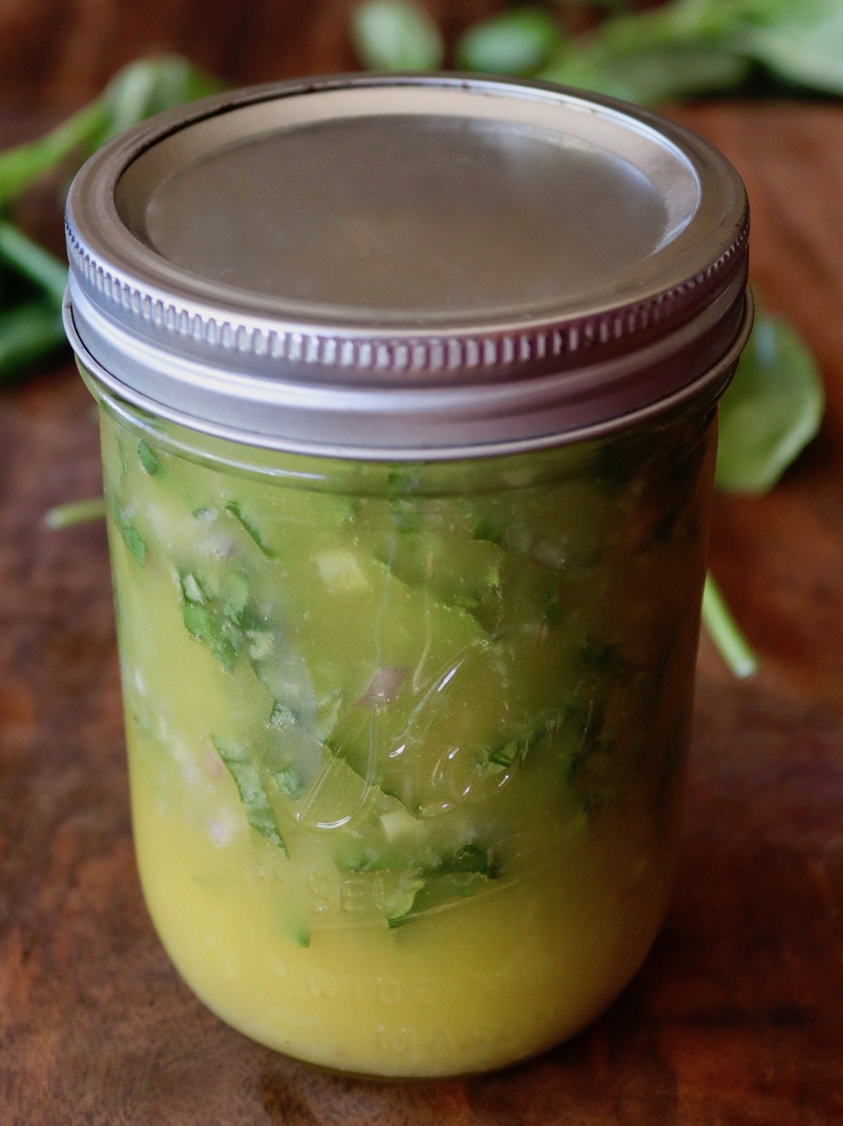 Mason jar with lid on of Lemon Basil Dressing.