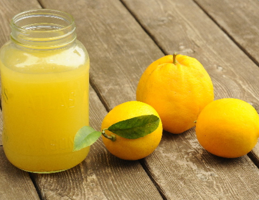 My Mom’s Meyer Lemonade Recipe in a Mason jar with a few lemons next to it on wooden table