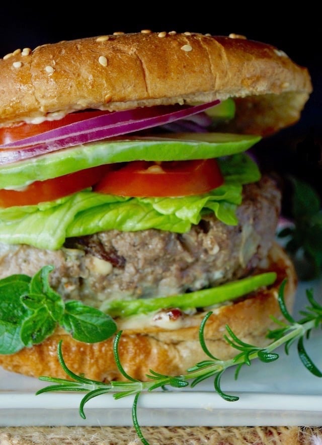 Close up of a Grilled Mediterranean Burger in a bun with all the fixins.