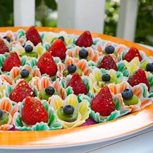 about a dozen bite-sized fruit tarts on orange-rimmed plate