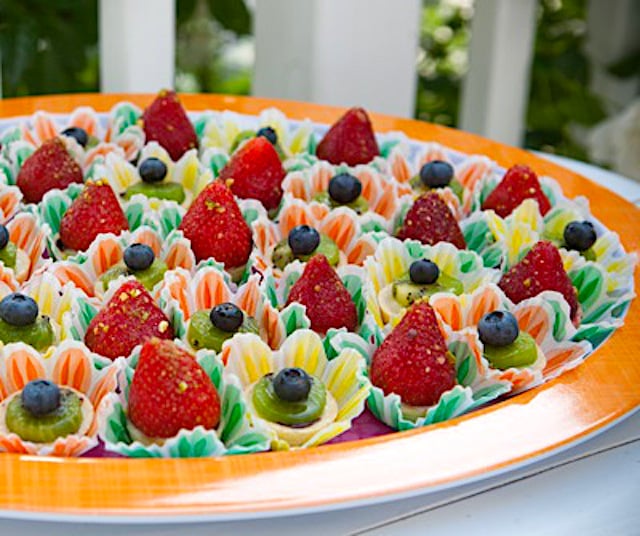 About a dozen bite-sized fruit tarts on orange-rimmed plate