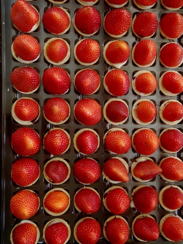 a couple of dozen Dessert Party Fresh Fruit Tartlets, lined up with strawberries