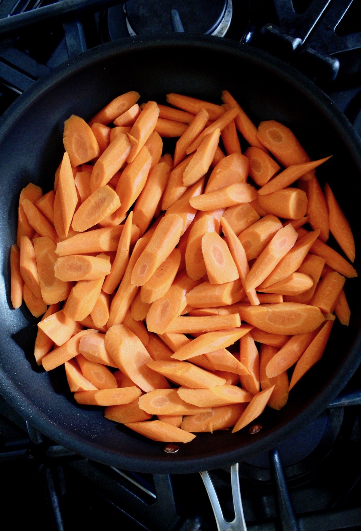 top view of saute pan with sliced raw carrots
