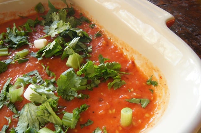 Baking dish with tomato sauce, cilantro, and green onions for Smoky Chipotle Breakfast Nachos with Eggs.