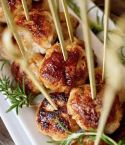 Rosemary Turkey Meatballs with Honey on a narrow white plate with toothpicks