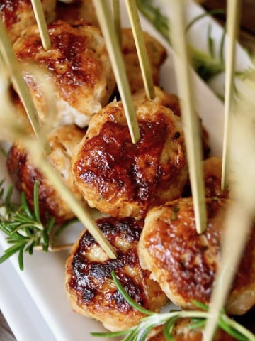 Rosemary Turkey Meatballs with Honey on a narrow white plate with toothpicks