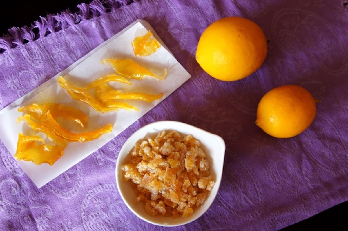 Candied-Citrus-Peels Candied lemon peels cut into strips and some chopped finely in a small white bowl, with two whole lemons next to them.
