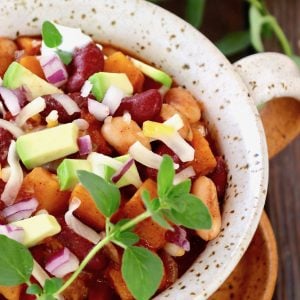 white speckled-rimmed bowl with suqash chili and oregano sprig