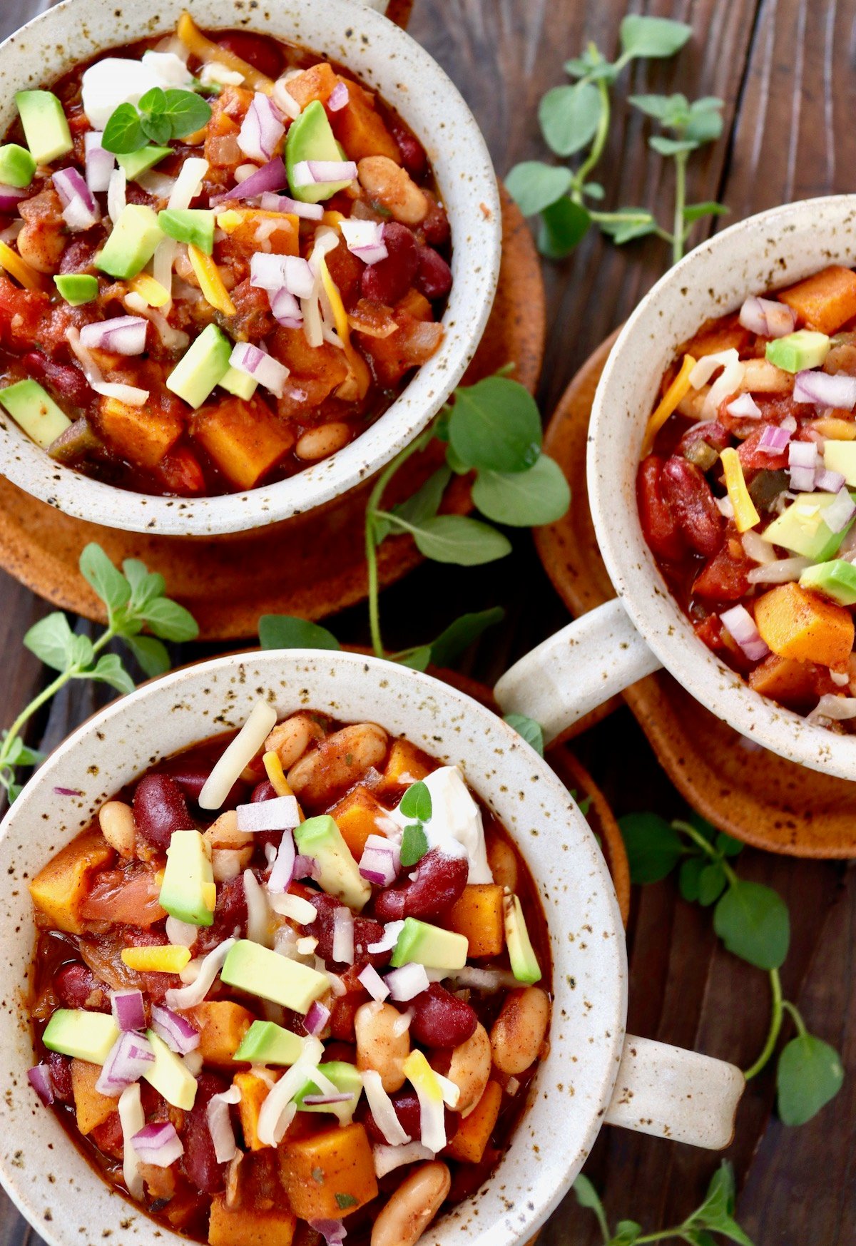 3 bowls of butternut squash chili with fresh oregano sprigs