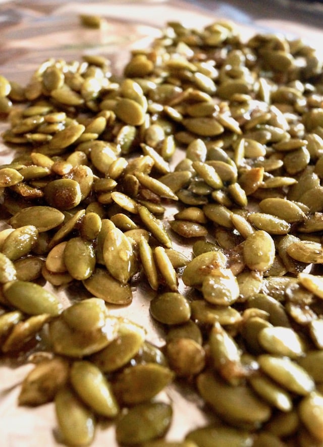 Raw spiced pepitas on a foil-lined baking sheet