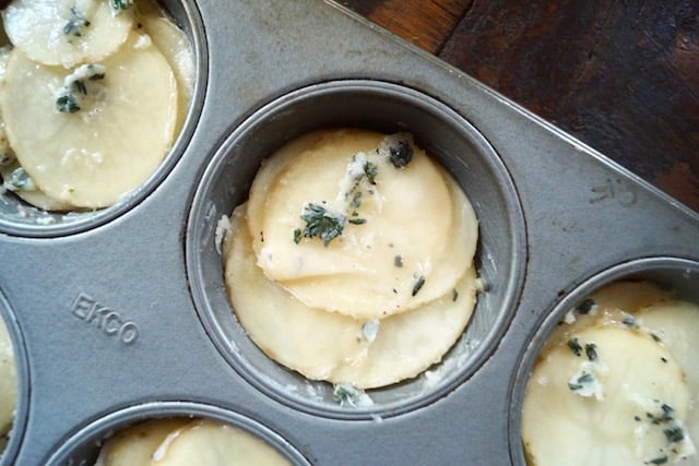 Thinly sliced potatoes mixed with butter and thyme arranged in muffin tin