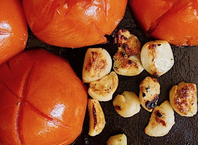 roasted garlic cloves and tomato halves on sheet pan