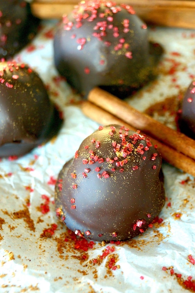 Spicy Mayan Chocolate Truffles with red sprinkles and cinnamon sticks on parchment paper.