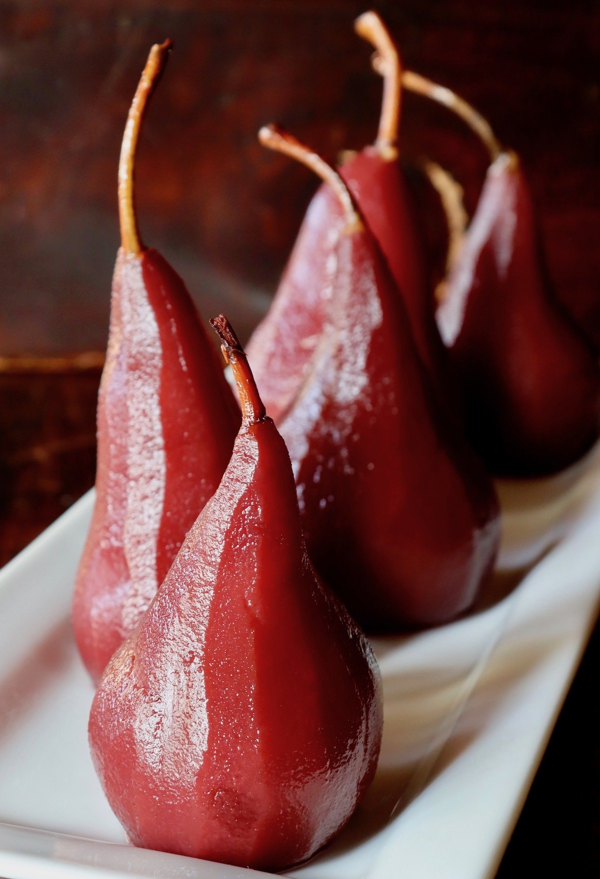 sveral whole port wine poached pears standing up.