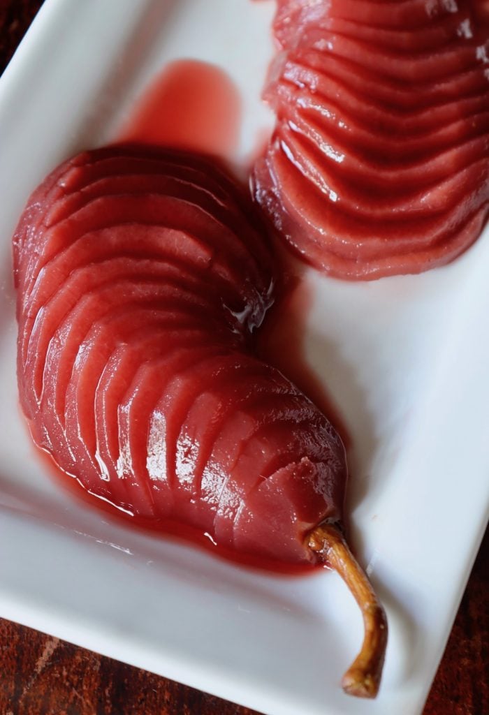 red port wine poached pear halves thinly sliced on a white plate