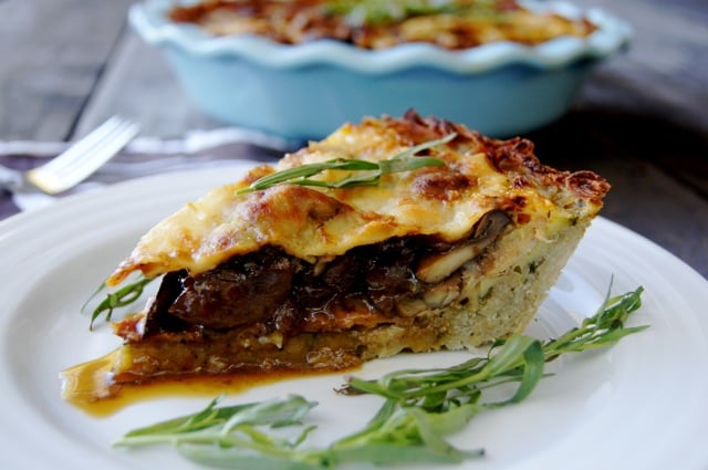 Slice of Mushroom Bacon Savory Pie on a white plate with fresh tarragon.