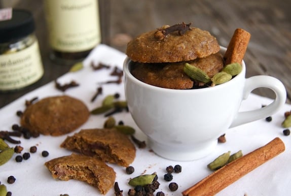 a few chai chocolate cookies with whole cinnamon, peppercorns and cardamom in a white coffee cup