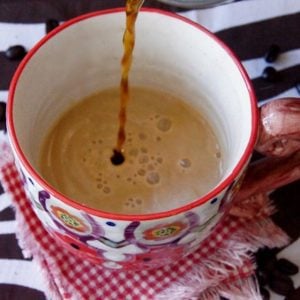 Coffee being poured into decoratively painted ceramic mug