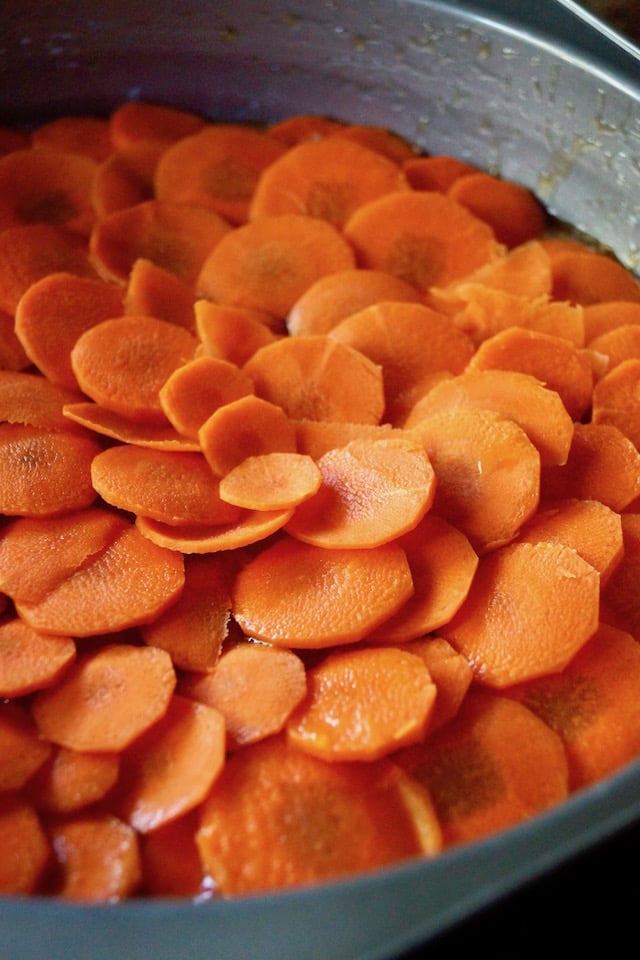 Round carrot slices covering the bottom of a cake pan in overlapping layers.
