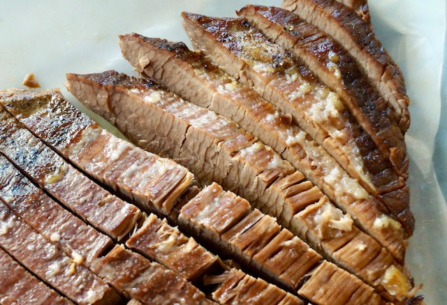 Sliced brisket on white parchment paper.