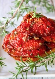 tomato confit with fresh rosemary on toast on white plate
