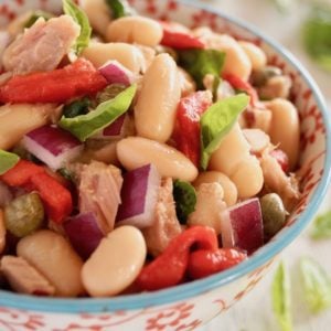 Close up of Cannelllini Bean Tuan Salad i a white bowl with blue trim and red flowers on it.