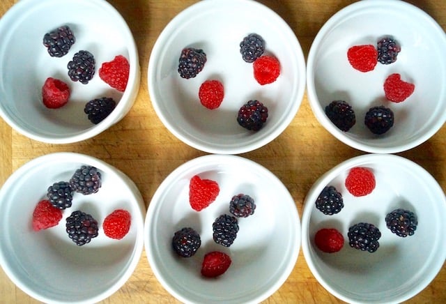 6 white ramekins with blackberries and raspberries in them.