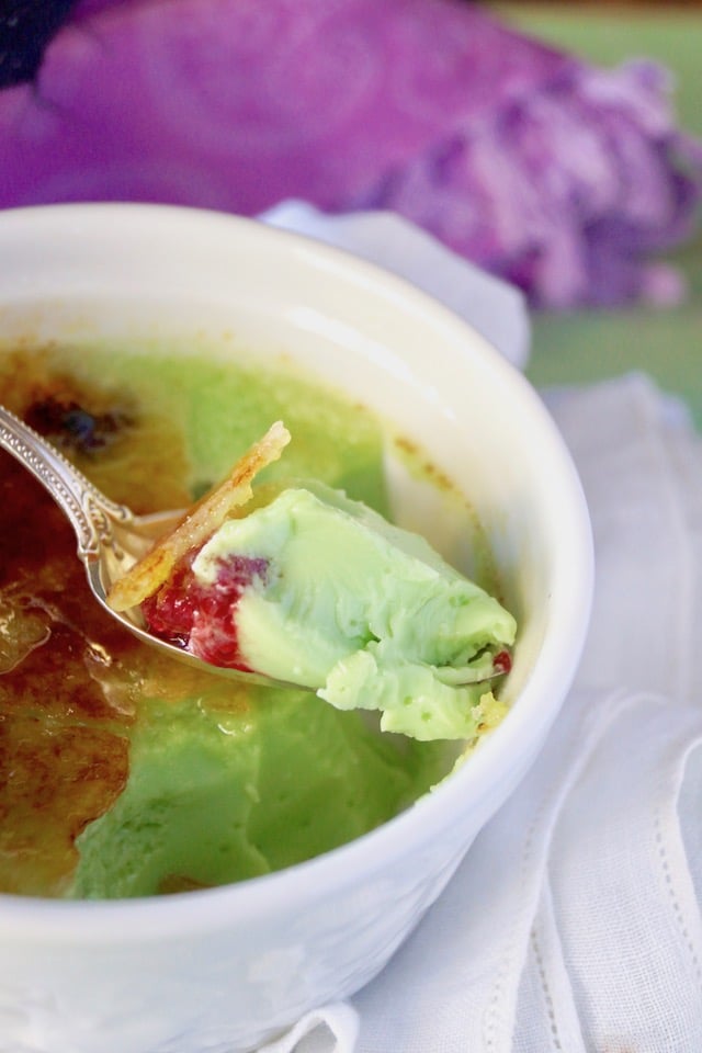 Close up of a bite of Coconut-Pandan Creme Brulee with a raspberry.