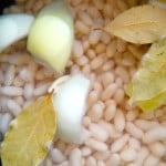 White beans with onion and bay leaves beneath wate to cook