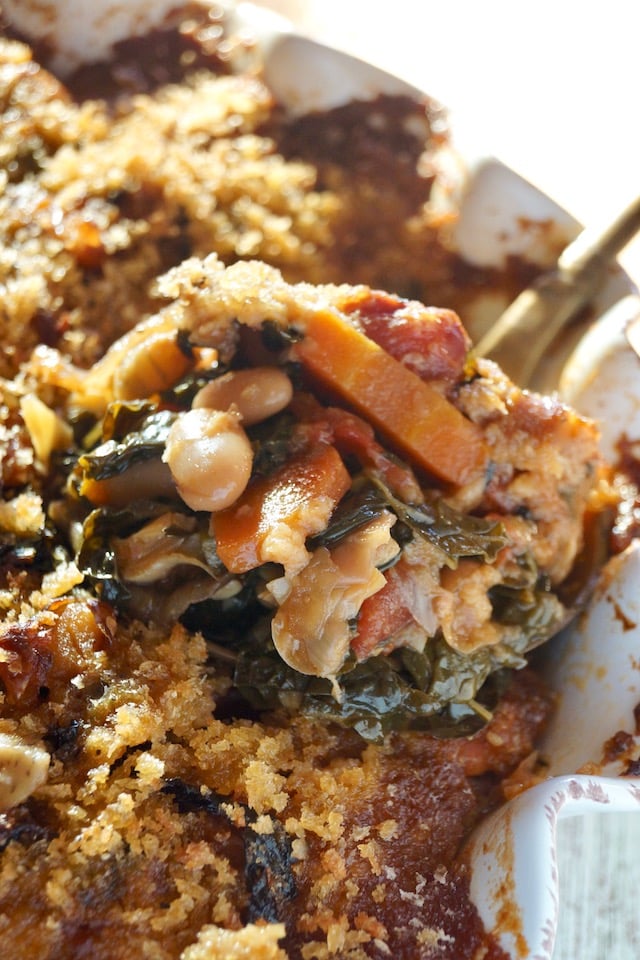 Large spoonful of Vegetarian Cassoulet held over pie dish.