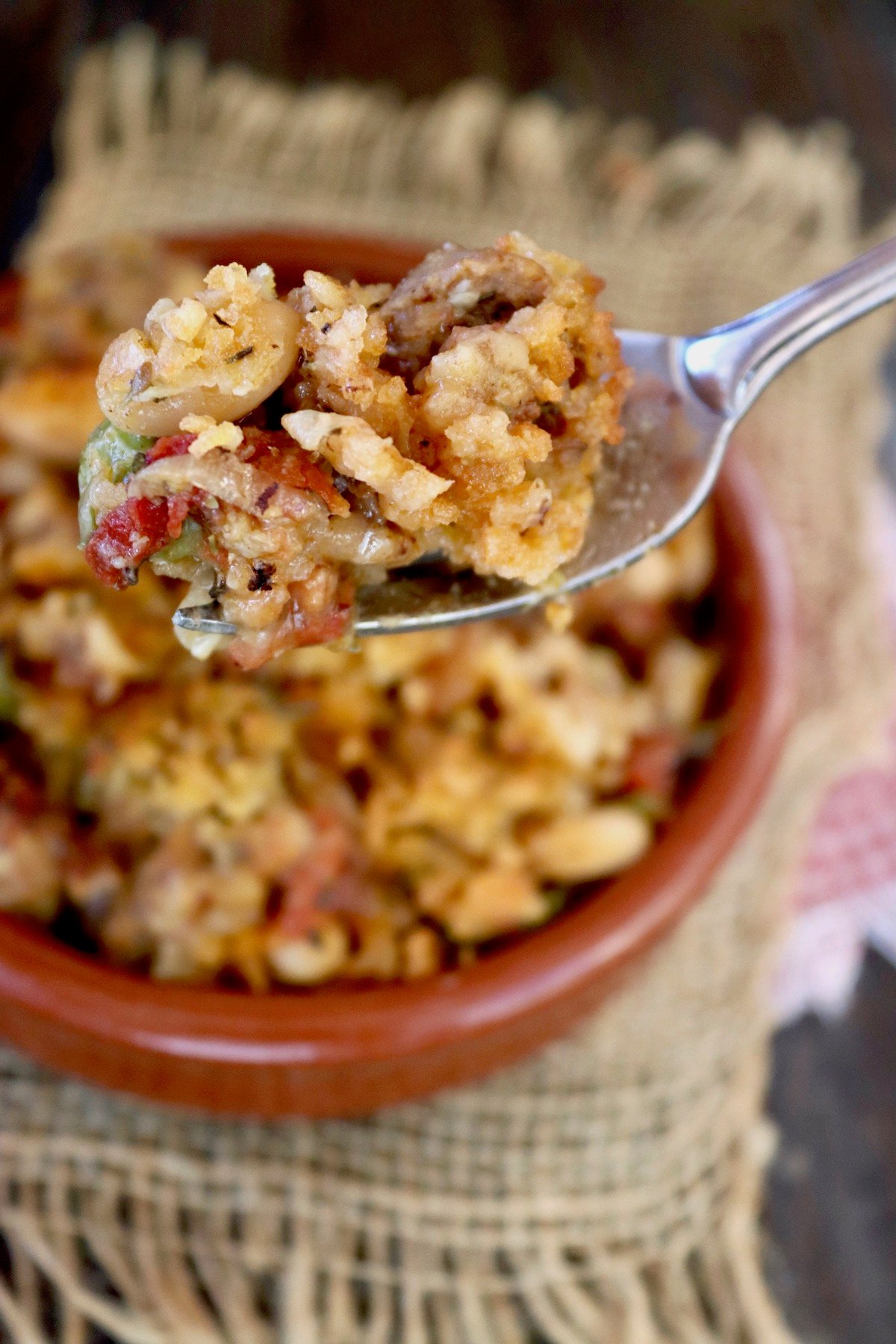 Cassoulet in terra cotta ramekin with one bite on a fork