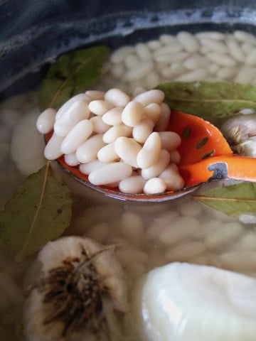 Cannellini beans in a slotted orange mixing spoon