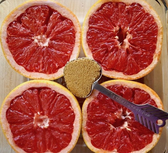 four grapefruit halves with heart-shaped measuring spoon with brown sugar