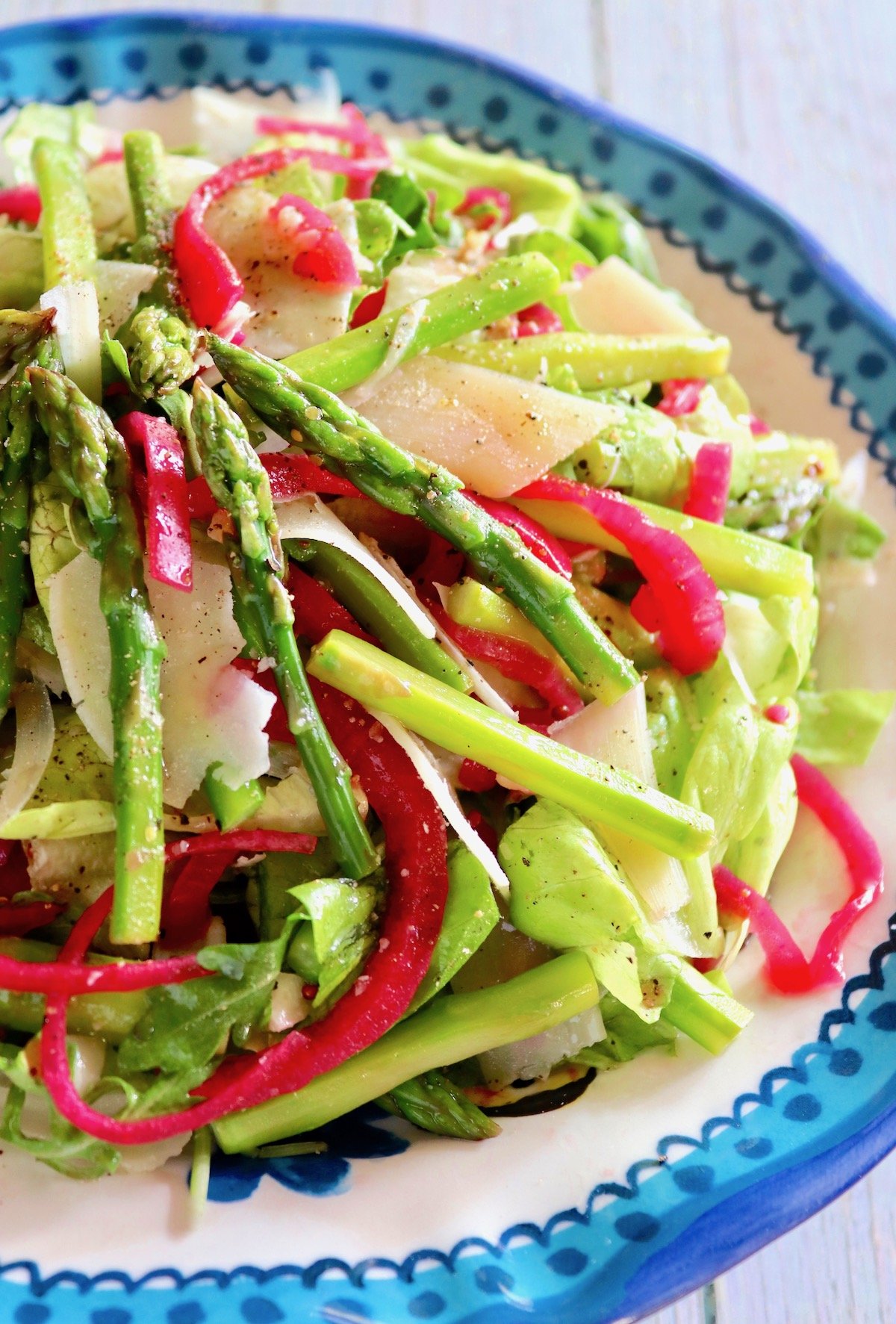 Blue-rimmed plate with asparagus salad and pickled red onions