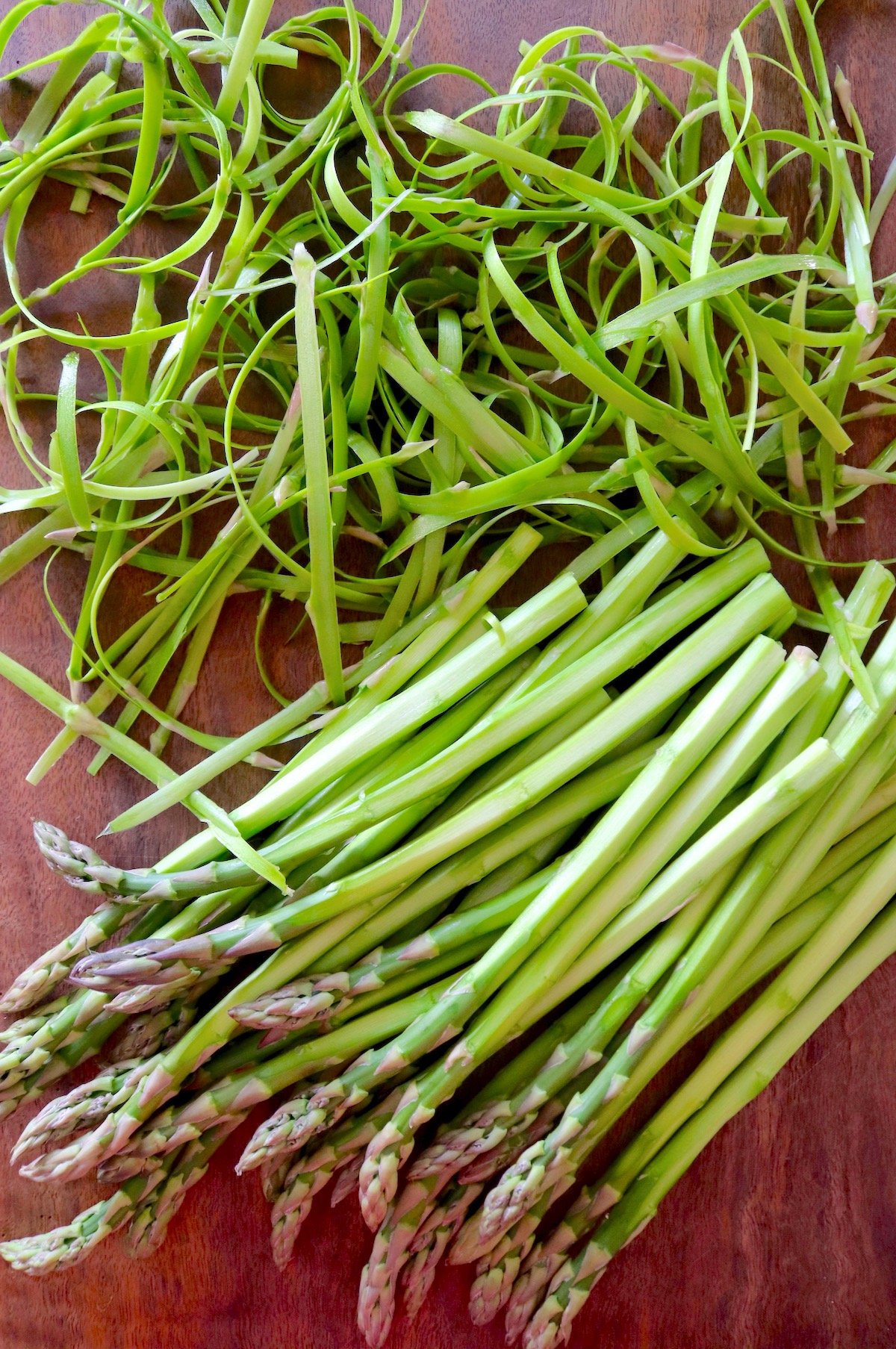 many peeled asparagus spears with peels next to them