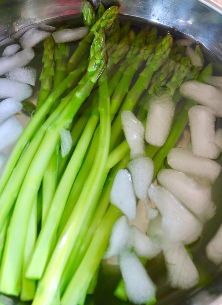 steamed asparagus spears in ice water