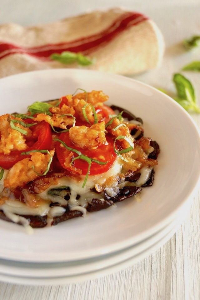 Grilled Sausage Portobello Mushroom Pizza on a white plate with basil leaves